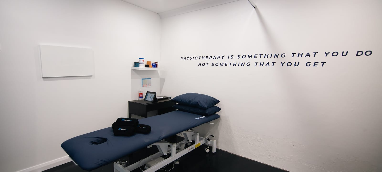 A treatment room at SportsFit Five Dock with the wall line "Physiotherapy is something that you do, not something that you get"